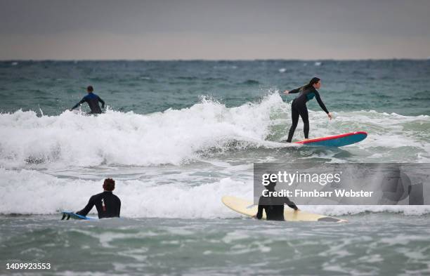 Surfers enjoy the waves in the sea at Polzeath beach on July 20, 2022 in Polzeath, United Kingdom.