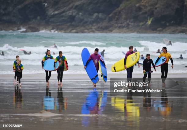 People leave the sea carrying their surfboards at Polzeath beach, on July 20, 2022 in Polzeath, United Kingdom.