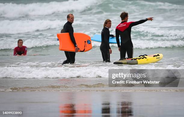 Lifeguard, carrying a rescue board, directs bodyboarders to surf between the red and yellow flags in the sea at Polzeath beach, on July 20, 2022 in...