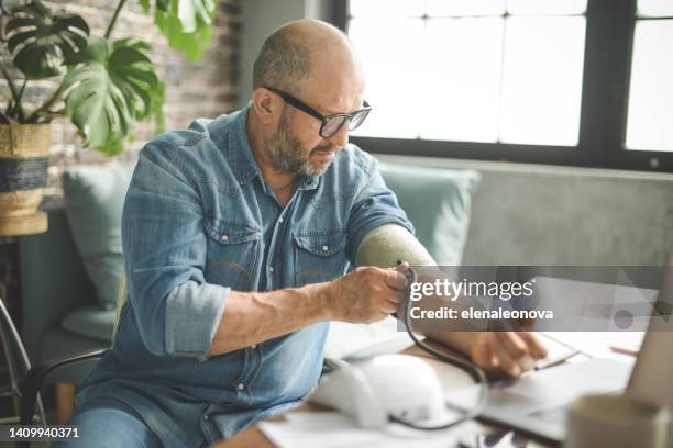 mature adult man working from office (with a classic tonometer measuring) - arteries stock pictures, royalty-free photos & images