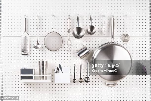 neatly arranged stainless steel kitchenware hanging on pegboard - tidy stock-fotos und bilder