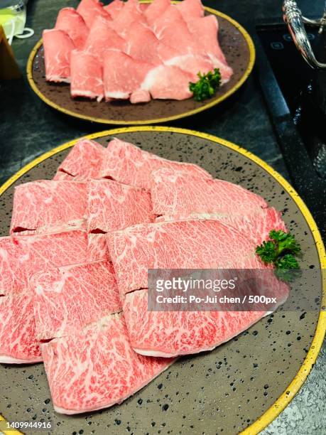 high angle view of meat in plate on table - sukiyaki stock-fotos und bilder
