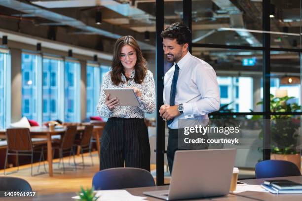 business man and woman standing working together on a digital tablet. - business couple showing stockfoto's en -beelden