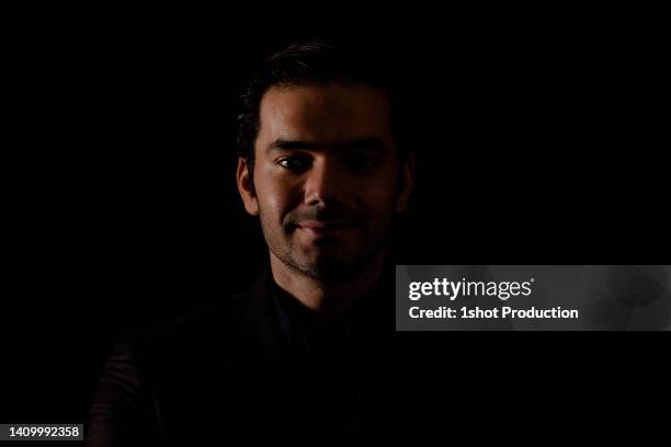 ハイコントラストの暗い背景の若い男性の肖像画。 - ローキー ストックフォトと画像