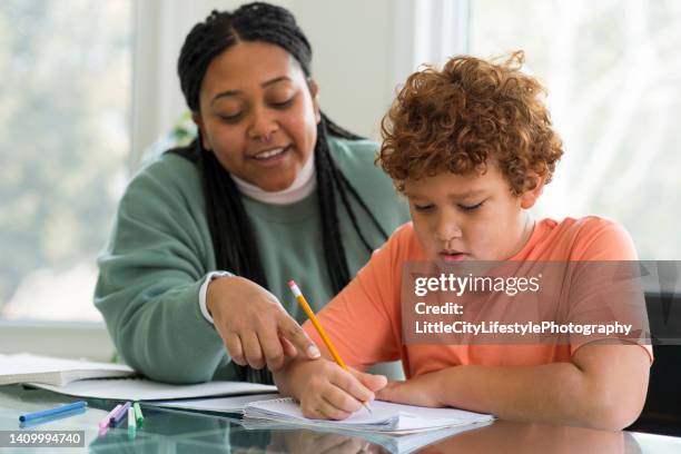 mother gently correcting her sons homework - teachers imagens e fotografias de stock