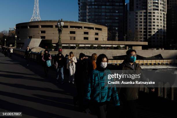 People wearing masks walk past Arts Centre Melbourne on July 21, 2022 in Melbourne, Australia. Victoria recorded 14,312 official cases of COVID-19 in...