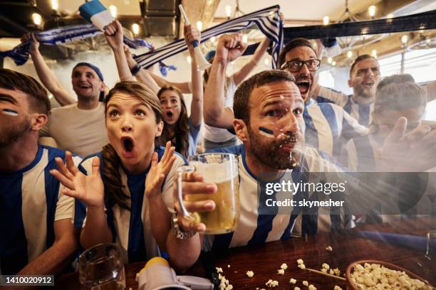 alegres fanáticos de los deportes viendo un exitoso partido en la televisión en un bar. - spit fotografías e imágenes de stock