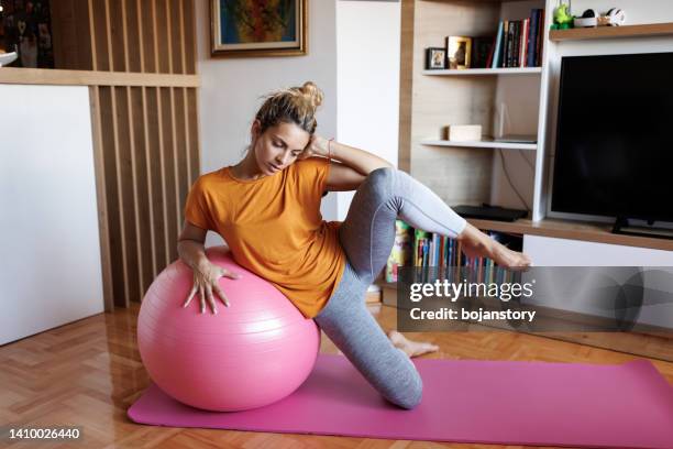 mujer joven haciendo ejercicio con una pelota de fitness en casa - yoga ball fotografías e imágenes de stock