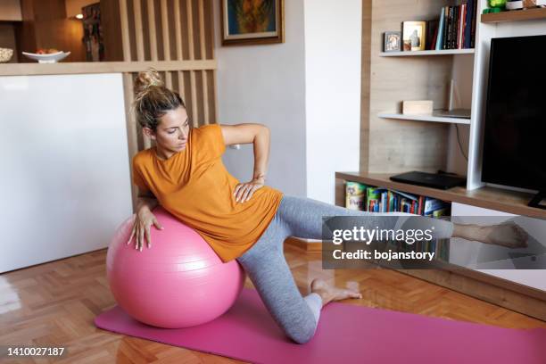 mujer joven haciendo ejercicio con una pelota de fitness en casa - yoga ball fotografías e imágenes de stock