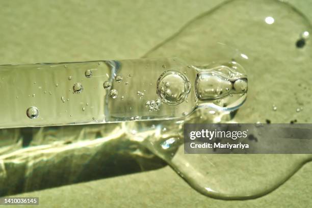 pipette with cosmetic serum with a beautiful drop of gel on a green background. perfectly demonstrate the texture of your gel product. - blood serum stock pictures, royalty-free photos & images