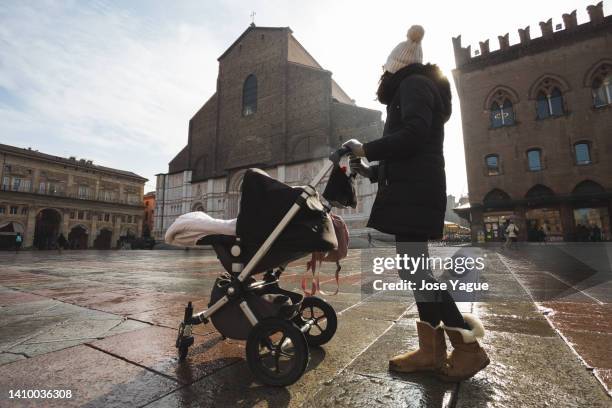 woman walking with a baby stroller in the rain - mother protecting from rain stockfoto's en -beelden