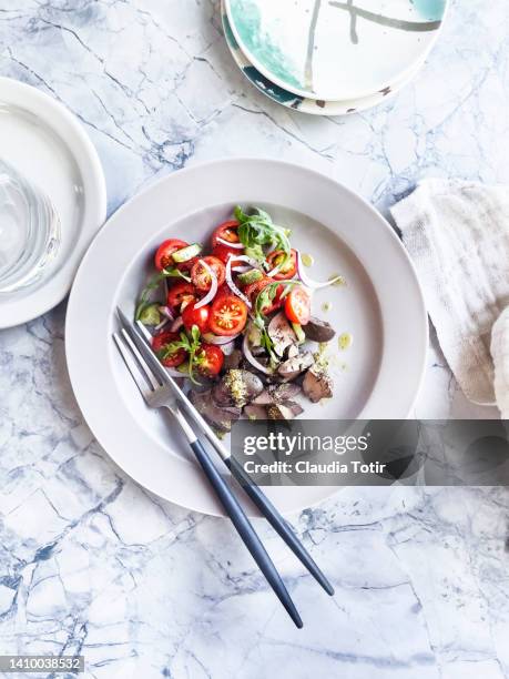 plate of roasted chicken liver with tomato salad on white, marble background - offal stock pictures, royalty-free photos & images