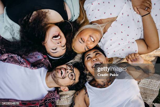 portrait of a group of friends laying down on a picnic blanket - fat man lying down stock pictures, royalty-free photos & images