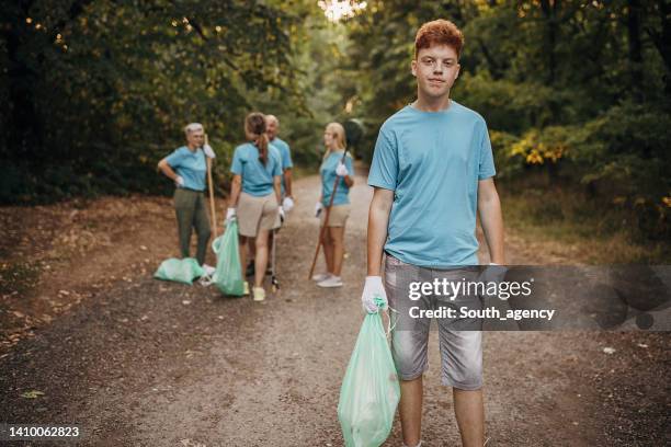 porträt eines jungen freiwilligen mit plastiktüte in der natur - social services stock-fotos und bilder