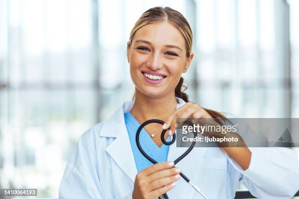 female cardiologist doctor at the hospital smiling and making a heart shape - making heart shape stock pictures, royalty-free photos & images