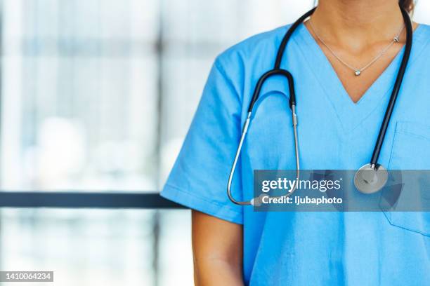 médico irreconocible con uniforme médico azul con estetoscopio alrededor del cuello. - estetoscopio fotografías e imágenes de stock