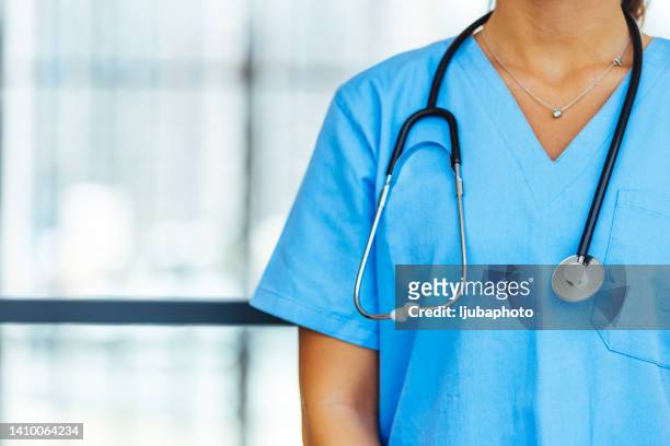 unrecognizable female physician in blue medical uniform with stethoscope around neck. - stethoscope stockfoto's en -beelden
