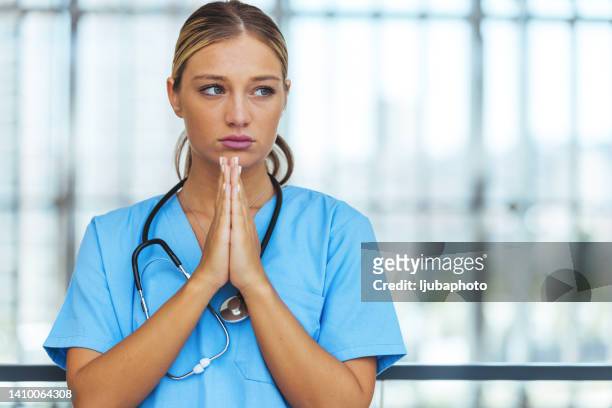 exhausted female surgical nurse takes break - sad nurse stock pictures, royalty-free photos & images