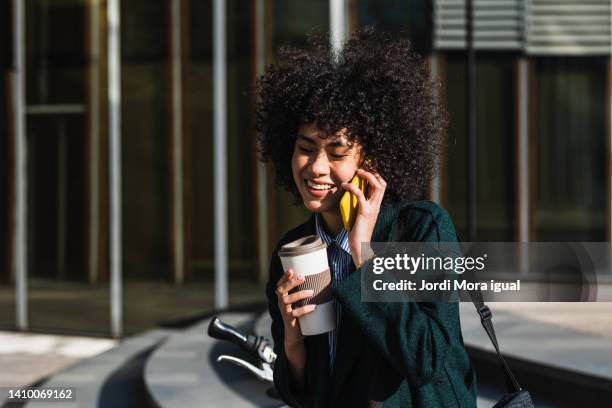 smiley woman using a mobile while drinking a take away coffee - stylish woman streets europe cellphone stockfoto's en -beelden