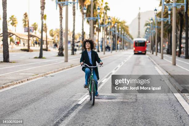 woman riding a bike in the middle of the road in the city - motociclista fotografías e imágenes de stock