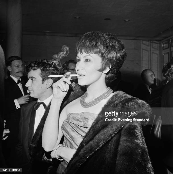 American actress and singer Chita Rivera, smoking a cigarette in a cigarette holder, attends the Evening Standard Drama Awards for 1961, held at the...
