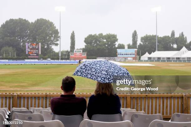 Spectators use an umbrella to shelter from the rain as rain stops play during the LV= Insurance County Championship match between Derbyshire and...