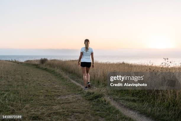 woman walking at dawn in the mountain - laufen und gras und sport stock-fotos und bilder