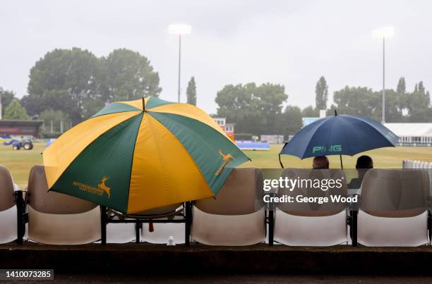 Spectators use an umbrella to shelter from the rain as rain stops play during the LV= Insurance County Championship match between Derbyshire and...