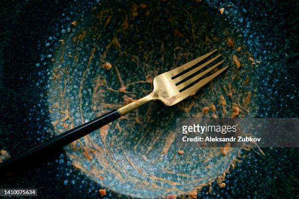 a dirty empty plate and fork on a wooden kitchen or dining table. cutlery is used, symbolizing the end of lunch or dinner. - messy table after party stock-fotos und bilder