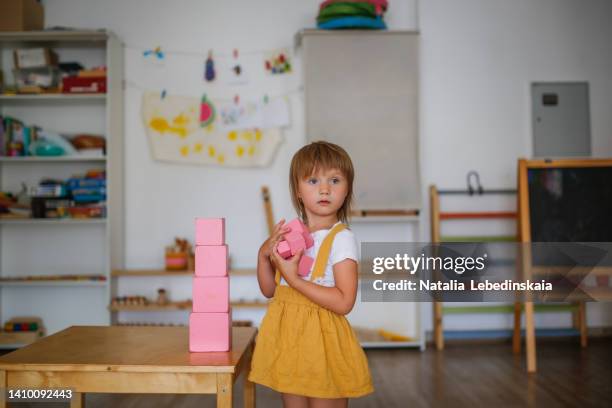 child builds a pink tower on table in montessori kindergarten - モンテッソーリ教育 ストックフォトと画像