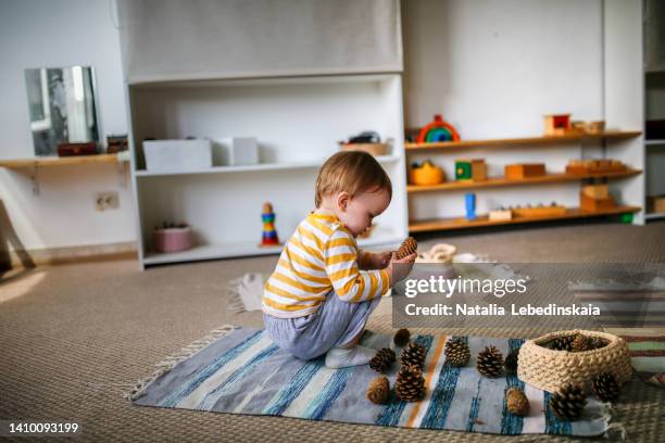 child playing with wooden cones on floor mat in montessori kindergarten, - montessori education stock pictures, royalty-free photos & images