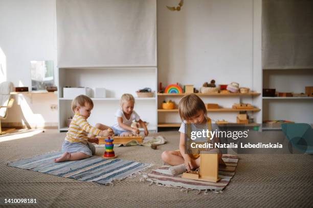 children focus on playing with eco-friendly natural toys on the floor in a bright room, - preschool age photos et images de collection