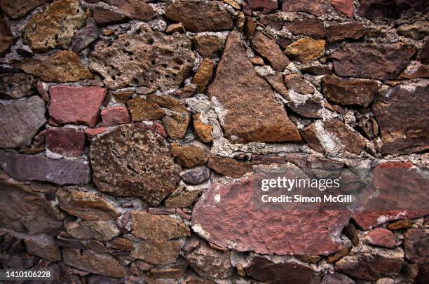 stacked pink, brown and purple stone wall with small stones inserted in the mortar gaps between the large ones - big puzzle photos et images de collection