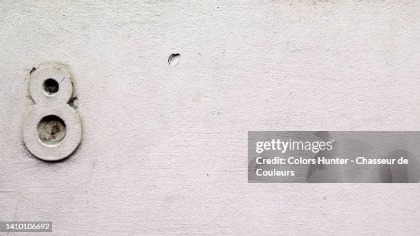 white painted and weathered concrete wall with the number 8 in brussels, belgium - typographies stock-fotos und bilder