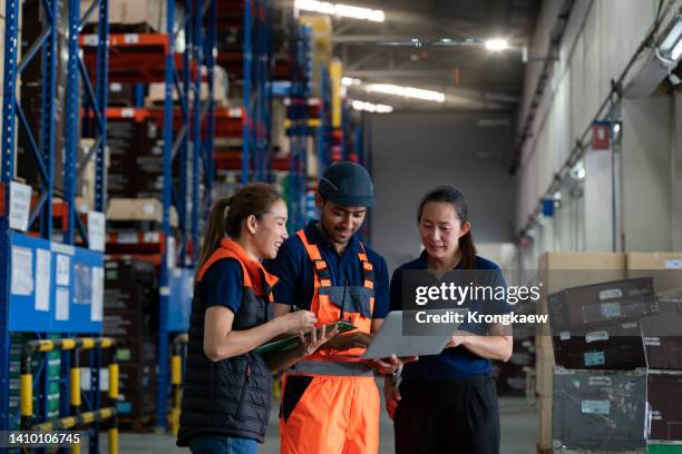 a small group of warehouse workers has a briefing in a large distribution center. - logistik stock-fotos und bilder