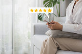 Woman customer hand pressing on smartphone screen with choose five star rating feedback icon and press level excellent rank for giving best score point to review the customer service.