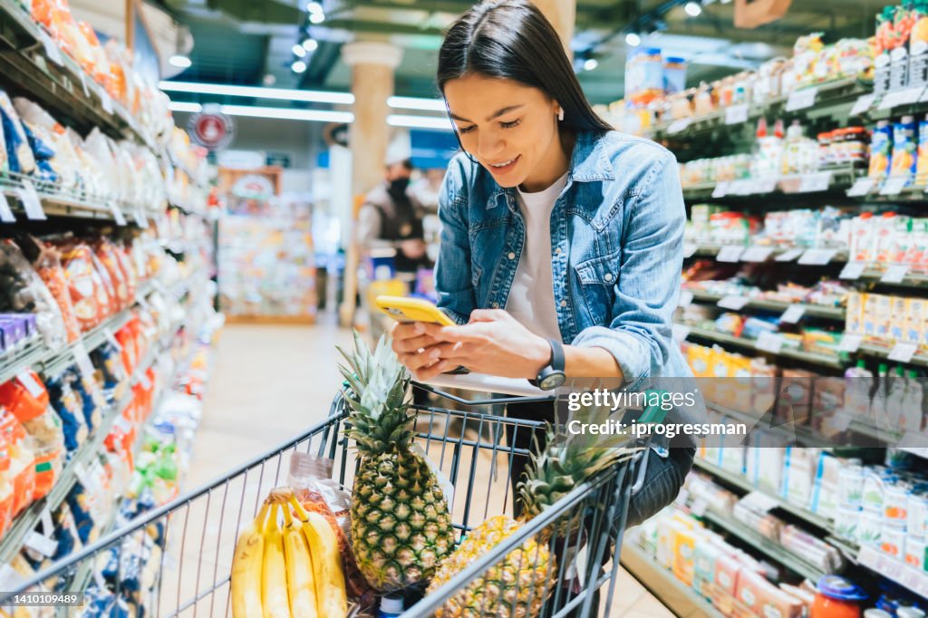 Happy young woman shopping for groceries in supermarket