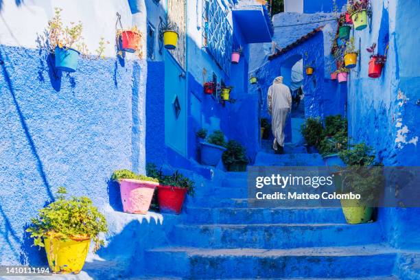 man walking on blue stairway, morocco - man blue background fotografías e imágenes de stock