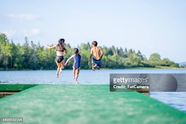children running off a dock - canada lake stock pictures, royalty-free photos & images
