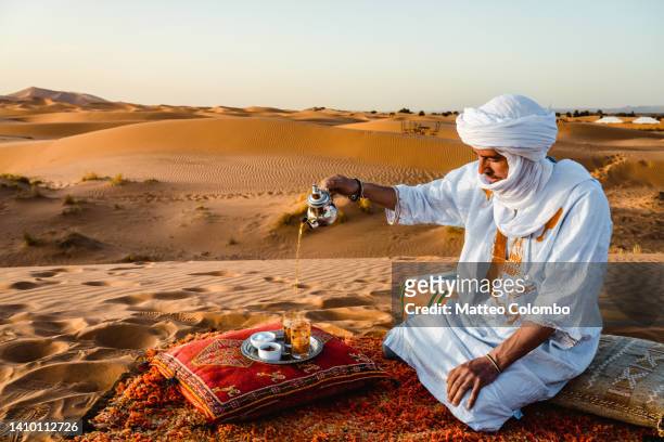 berber man serving tea in the desert, morocco - toeareg stockfoto's en -beelden
