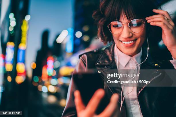 portrait of smiling woman listening music while using mobile phone at night,new york,united states,usa - nyc nightlife stock pictures, royalty-free photos & images