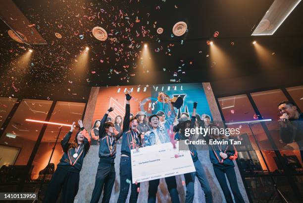 asiatisches esports-team mit trophäen-mock-up-scheck, der den sieg feiert und das große finale auf der bühne anfeuert. videospiel championship arena. cyber games turnier event - esports veranstaltung stock-fotos und bilder