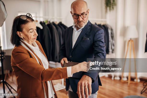 saleswoman and customer picking textile for suit - custom tailored suit stock pictures, royalty-free photos & images