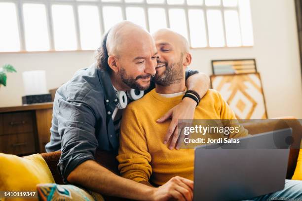 gay couple kissing on couch - gay men pic stock pictures, royalty-free photos & images