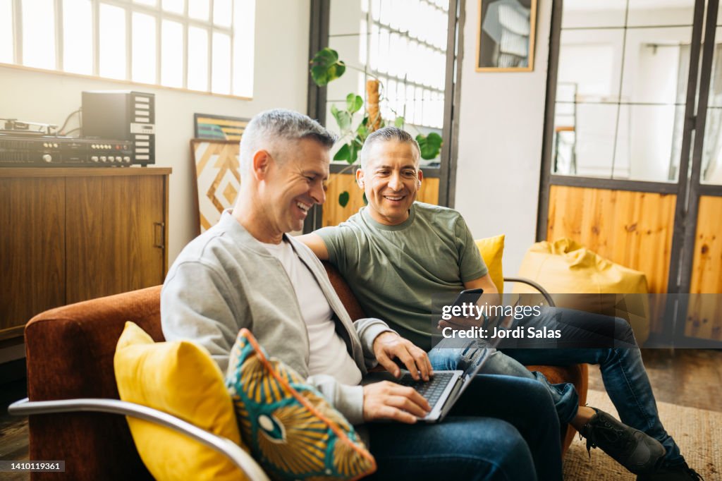 Gay couple on couch going over their home finances