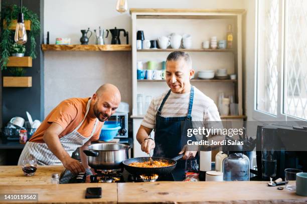 gay couples cooking in a kitchen - kochen freunde stock-fotos und bilder
