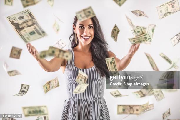 a young woman is throwing around a lot of dollar bills. lottery winning concept. - loto photos et images de collection
