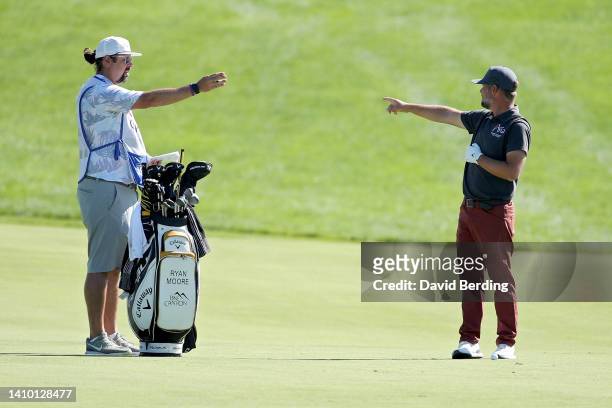 Ryan Moore of the United States and his caddie line up a shot on the seventh hole during the first round of the 3M Open at TPC Twin Cities on July...