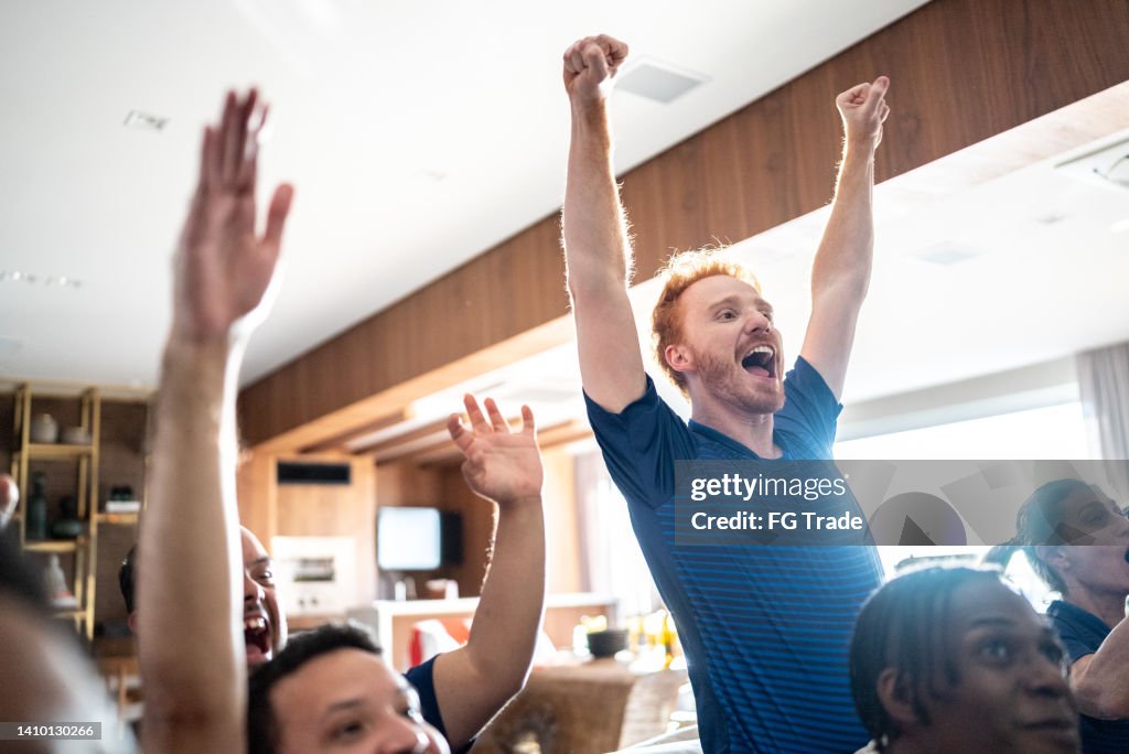 Sports fans celebrating while watching a match at home