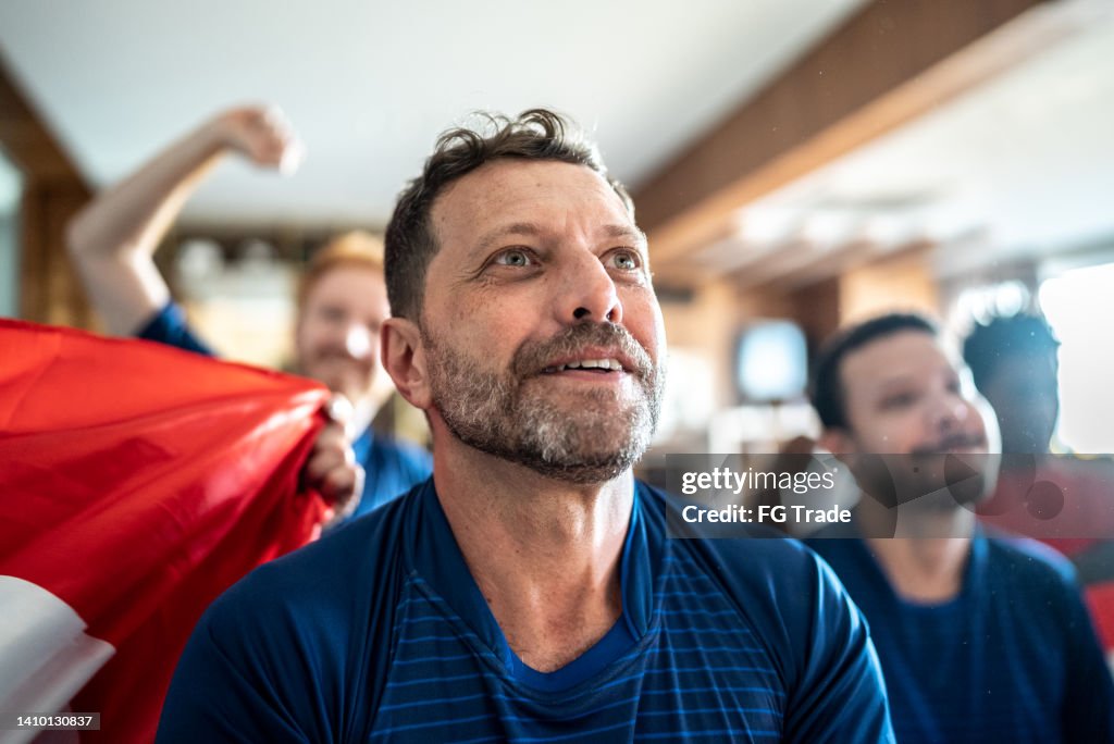 Reifer Mann, der einer Fußballmannschaft zusieht, die zu Hause mit Freunden ein Spiel spielt